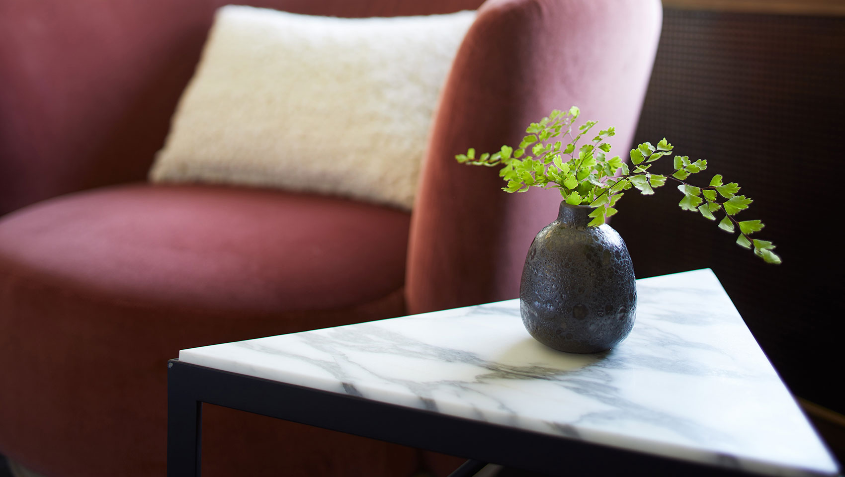 alton hotel bedside table with small plant and armchair