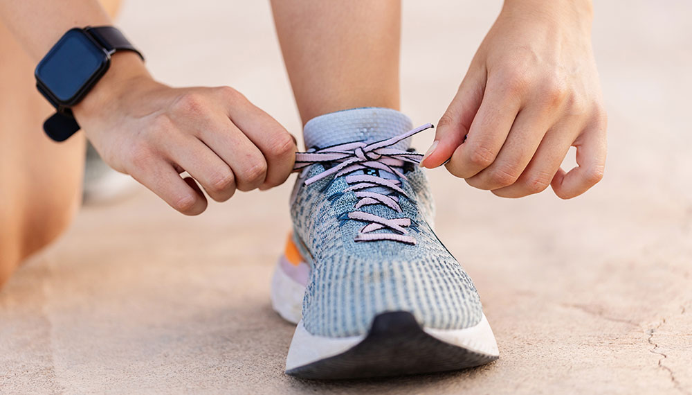 Runner wearing a smartwatch and tying their sneaker