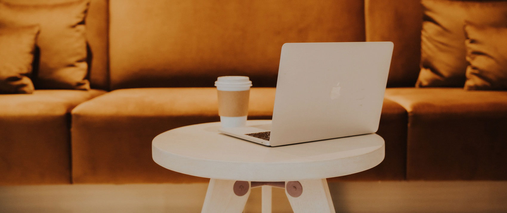computer and coffee cup on table in front of a couch